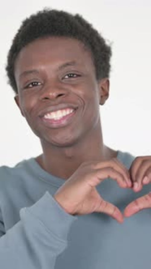 Smiling Young Man Makes Heart Shape with Hands