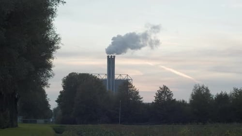 Polluting smoking factory chimney against a sunset in realtime