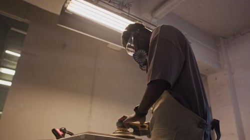 African American Carpenter Using Electric Sander in Workshop