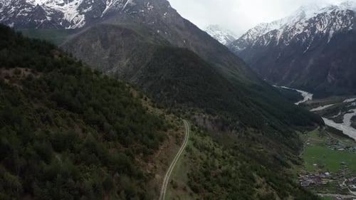 Winding Road through Steepy Mountain Range Covered with Dense Forest