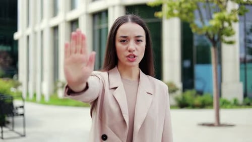 Woman Holds Hand Up In Stop Gesture Outdoors