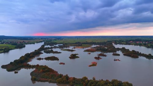 Sunset view of river islands and green fields under a cloudy sky.