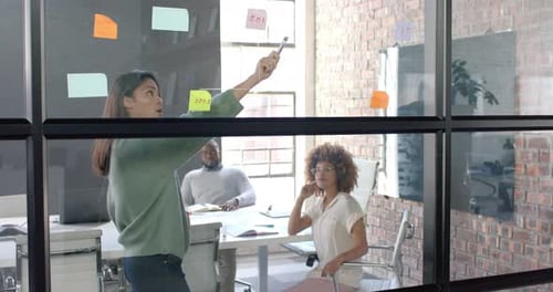 Divers collègues masculins et féminins discutent, réfléchissent devant un mur de verre au bureau, au ralenti