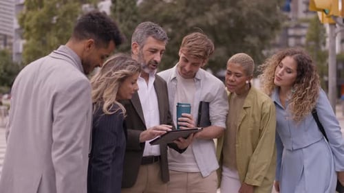 Team Looks at Tablet on City Street