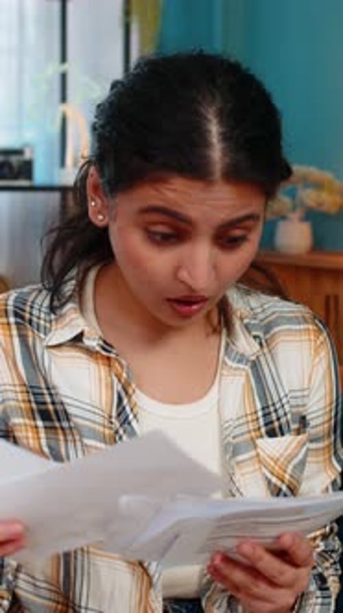 Woman Reviewing Troubling Paperwork Indoors