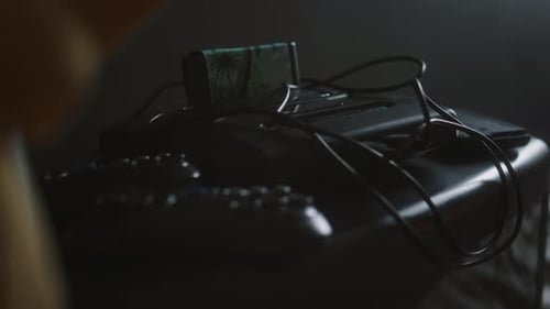 Close-up of Gaming Console with Inserted Cartridge and Two Gamepads