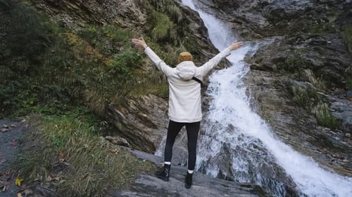 Beautiful Female Traveler Walks Hiking Route in the Alps and Enjoys the View of a Mountain River and