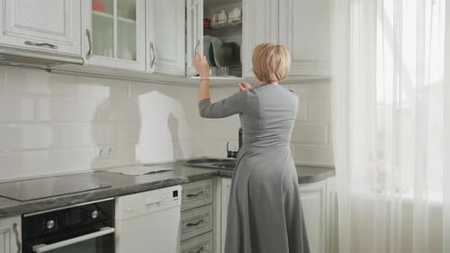 Woman Getting a Glass from Kitchen Cabinet