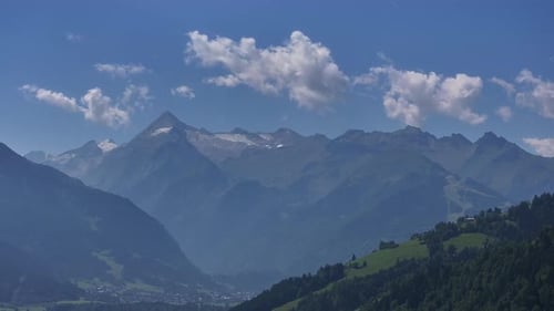 Jagged Mountain Summits Rise Above Scattered Clouds and Lush Forests