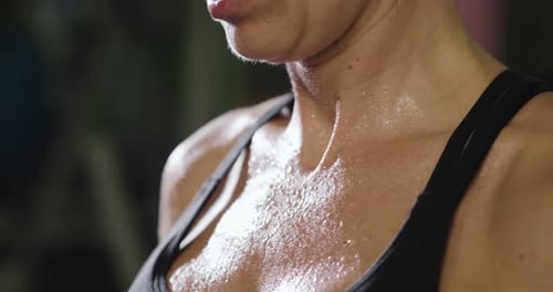 Close up of the body of a sporty and fit woman, who recovers her energy after sweating at the end
