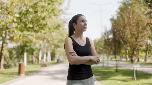 Confident Brunette Woman Relaxing After Outdoor Workout in Sunny Park