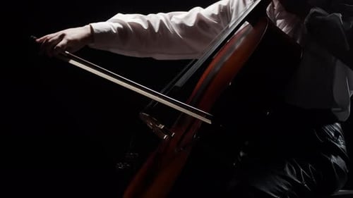 Female Musician Plays Classical Music on Cello While Sitting on Chair in Studio Dark Background Side