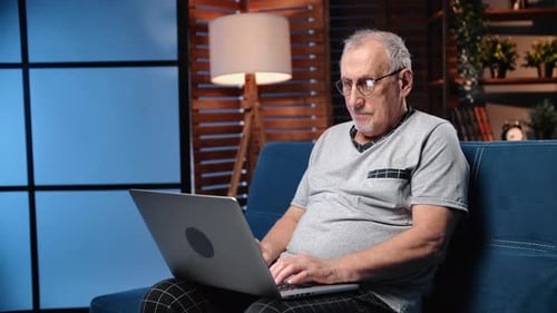 Senior Man Comfortably Using Laptop on Couch