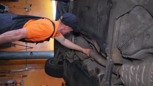 Mechanic Working on Vehicle in Garage Using Auto Parts