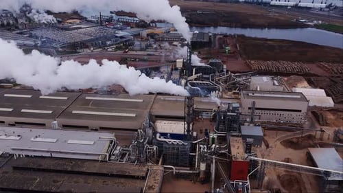 Thick White Smoke Rises From Riga Factory Near River on Cold Grey Winter Day