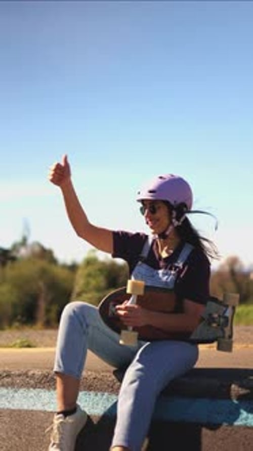 Woman with Skateboard Gives Thumbs Up