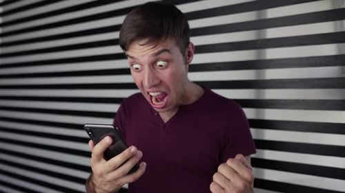 Excited male man winner looking at mobile phone using app celebrating success, hand gesture yes!