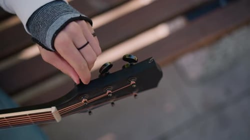 Un tranquilo entorno de parque con un músico, escena íntima del guitarrista ajustando las cuerdas, primer plano del músico