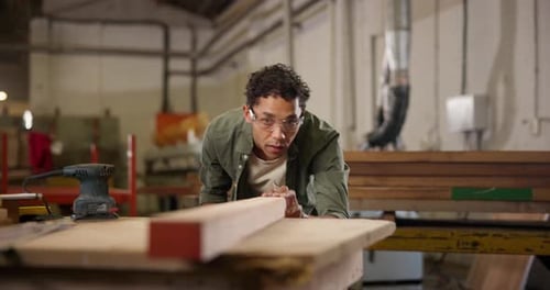 Young Adult Measures Wood in Workshop