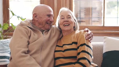 Smiling Senior Couple Hugging on Couch at Home