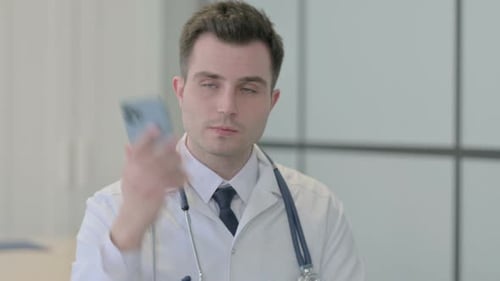 Young Doctor Answering a Phone Call in Office