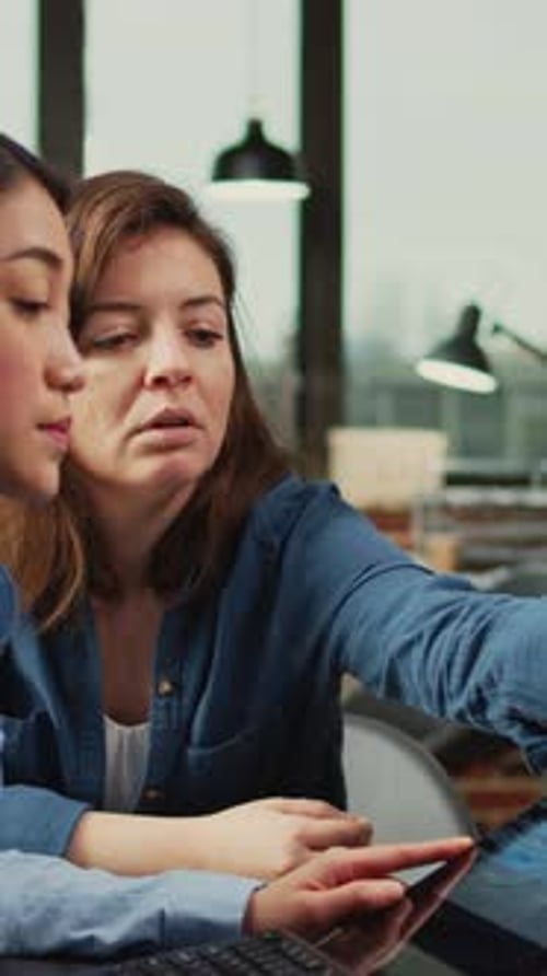 Two Women Collaborating on Graphics Tablet in Office