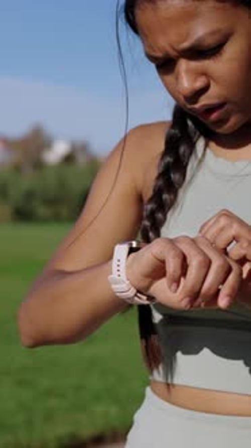 Woman Using Smartwatch Outdoors During Exercise Routine