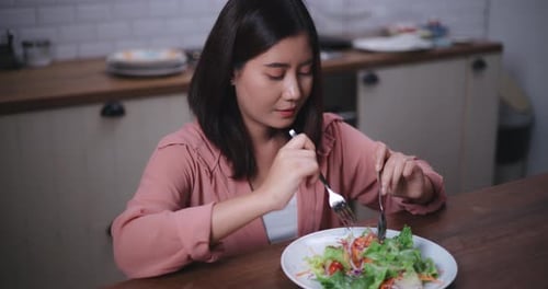 Woman Eating Salad in Kitchen