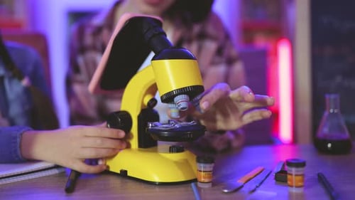 Child and Adult Using Microscope in Home Laboratory