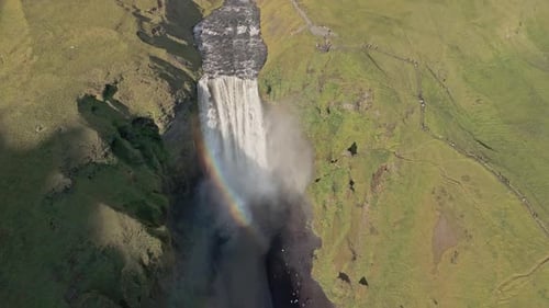 Aerial View Of Waterfall In Icelandic Mountains With Volcanic Glacier Behind