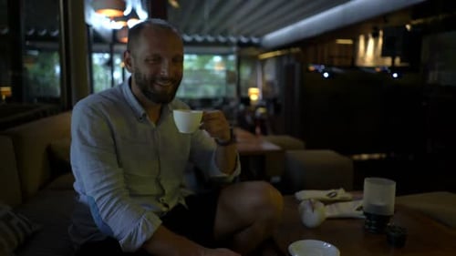 Young man enjoying morning coffee and relaxation in a sunny cafe garden