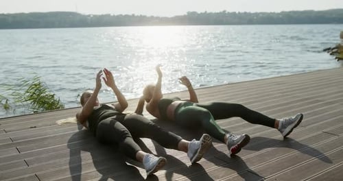 Tilt Down and Tilt Up View of Strong Female Athletes in Sportswear Lifting Legs and Touching Feet
