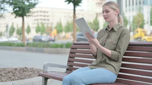 Woman Using Tablet on Park Bench in City