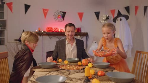 Family in Costumes Celebrating Halloween with Dinner