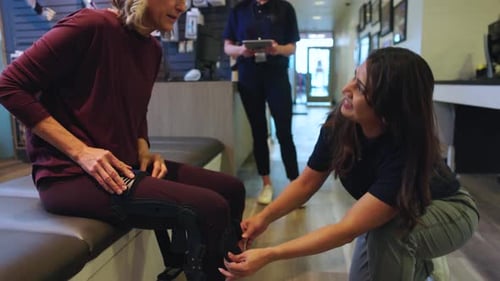 Physical Therapist Helping Senior Patient with Knee Brace in Clinic 10 Seconds or Greater