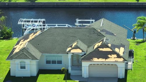Damaged House Roof with Missing Shingles After Hurricane Ian in Florida