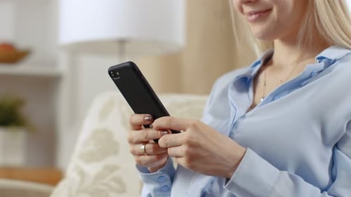 Close-up Of a Woman at Her Home Sitting on a Sofa and Using Her Smartphone.