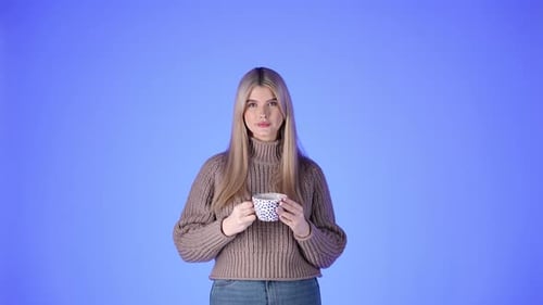 Young Woman Enjoying Hot Drink on Blue Background