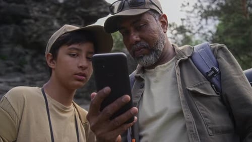 Man and Teen Using Phone in Nature