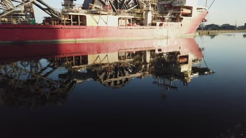 Red cable laying ship tilt shot from the reflection in Albert Dock Basin up to the berthed ship on a