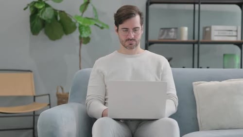 Man Uses Laptop on Sofa in Living Room
