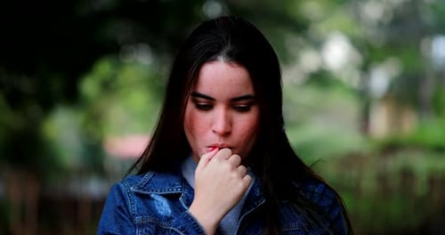 Pensive Woman Thinking and Biting Her Nails Outdoors