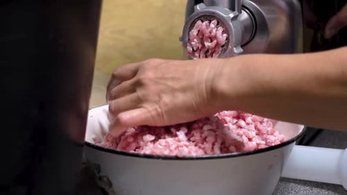 Metzger bewegen Hackfleisch von Hand durch eine Stahlschneidemühle, Nützlichkeit in der Küche, Nahaufnahme
