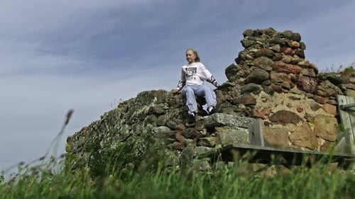 Child Sitting on Top of Stone Wall Ruins