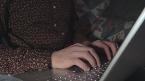 A medium shot of someone typing at their laptop keyboard