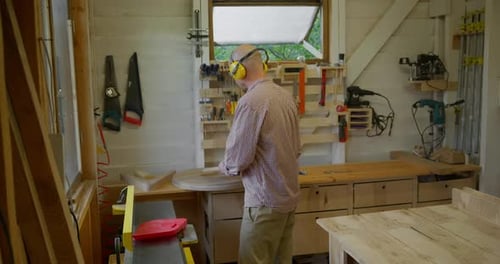 a Man Woodworker Working in His Tiny Workshop on a Jointing Machine