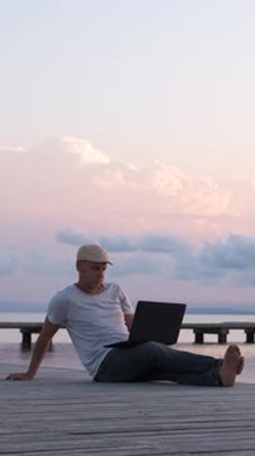 Viajante masculino sentado na praia usando o conceito de laptop, nômade digital ou trabalhador remoto