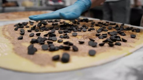 Bei der Herstellung von Zinnabons verwendet eine Bäckerin Schokolade in Granulat zum Backen