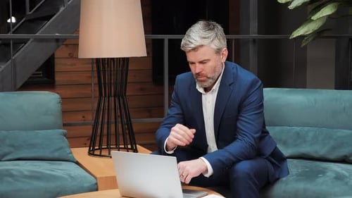 Thoughtful Pensive Businessman Working on Laptop Computer at Office Lobby