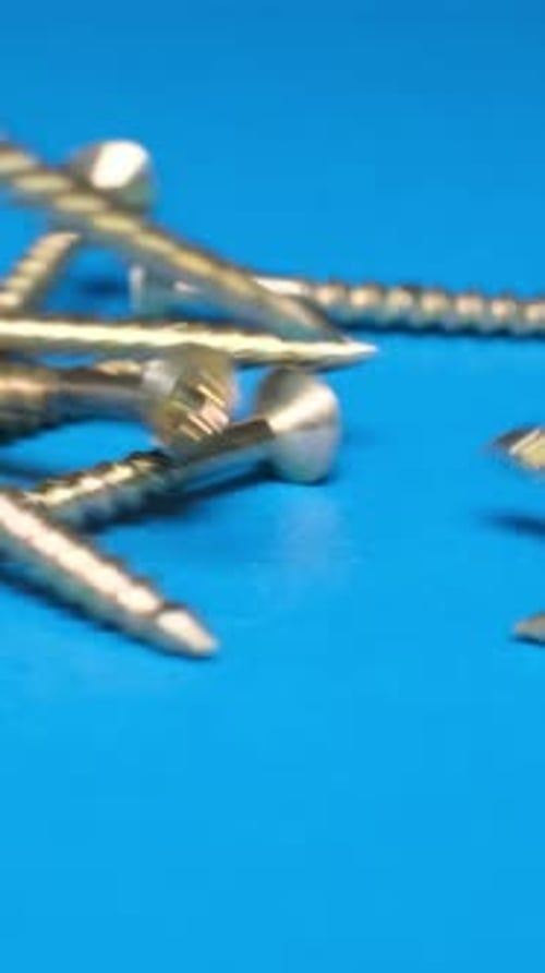 Metal Bolts Falling on a Blue Background in Slow Motion Vertical Video